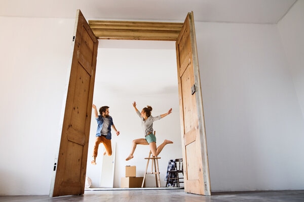 Young Couple Moving In A New House Jumping Up High